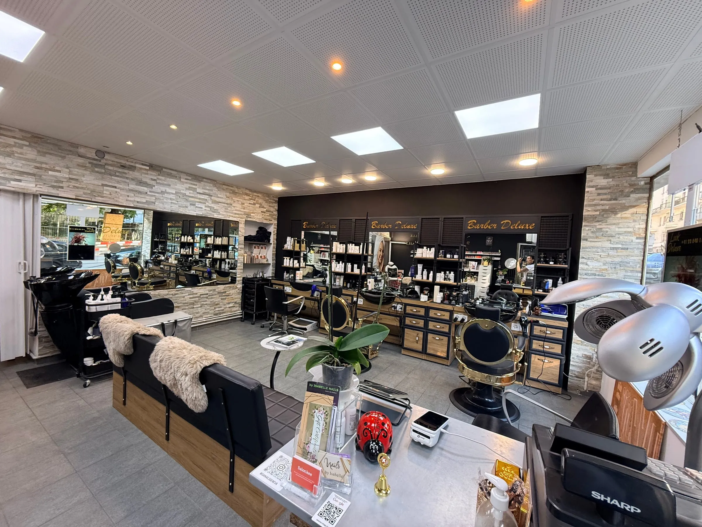 Intérieur du salon Look Deluxe aux Eaux-Vives : postes de coiffage, miroirs et casques séchoirs